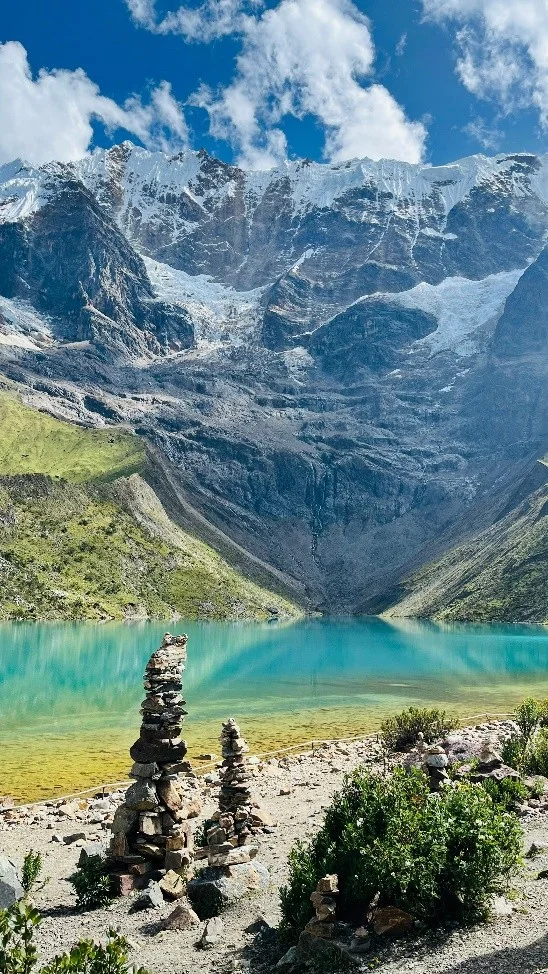 Laguna Humantay de aguas turquesas con apachetas de piedra en primer plano y el imponente nevado al fondo