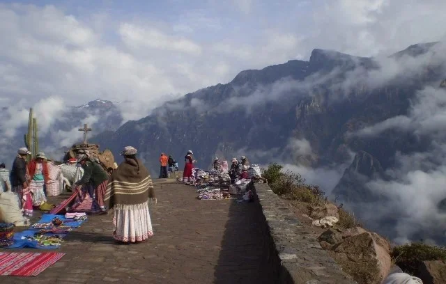 Mujeres con vestimenta tradicional venden artesanías en el mirador Cruz del Cóndor frente al Cañón del Colca